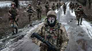 Украинские военнослужащие идут по дороге к своей базе недалеко от линии фронта в Донецкой области.