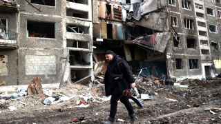 Мужчина с детским самокатом проходит мимо разрушенного в результате российской ракетной атаки жилого дома в городе Селидово Донецкой области.