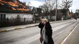 Женщина перед горящим после обстрела домом в городе Ирпень под Киевом.