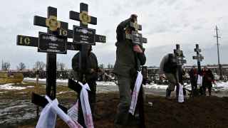 Работники кладбища устанавливают кресты на могилах семьи из пяти человек, в том числе троих детей, которые погибли в своем доме в результате пожара после атаки беспилотника ​​в Харькове 12 февраля 2024 года.