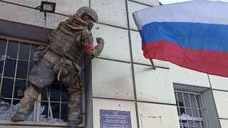 Российский военнослужащий вешает флаг на административное здание в Авдеевке.